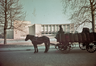 115628 Gezicht op de Stadsschouwburg (Lucasbolwerk) te Utrecht; op de voorgrond een paard en wagen met (aardappel?)zakken.